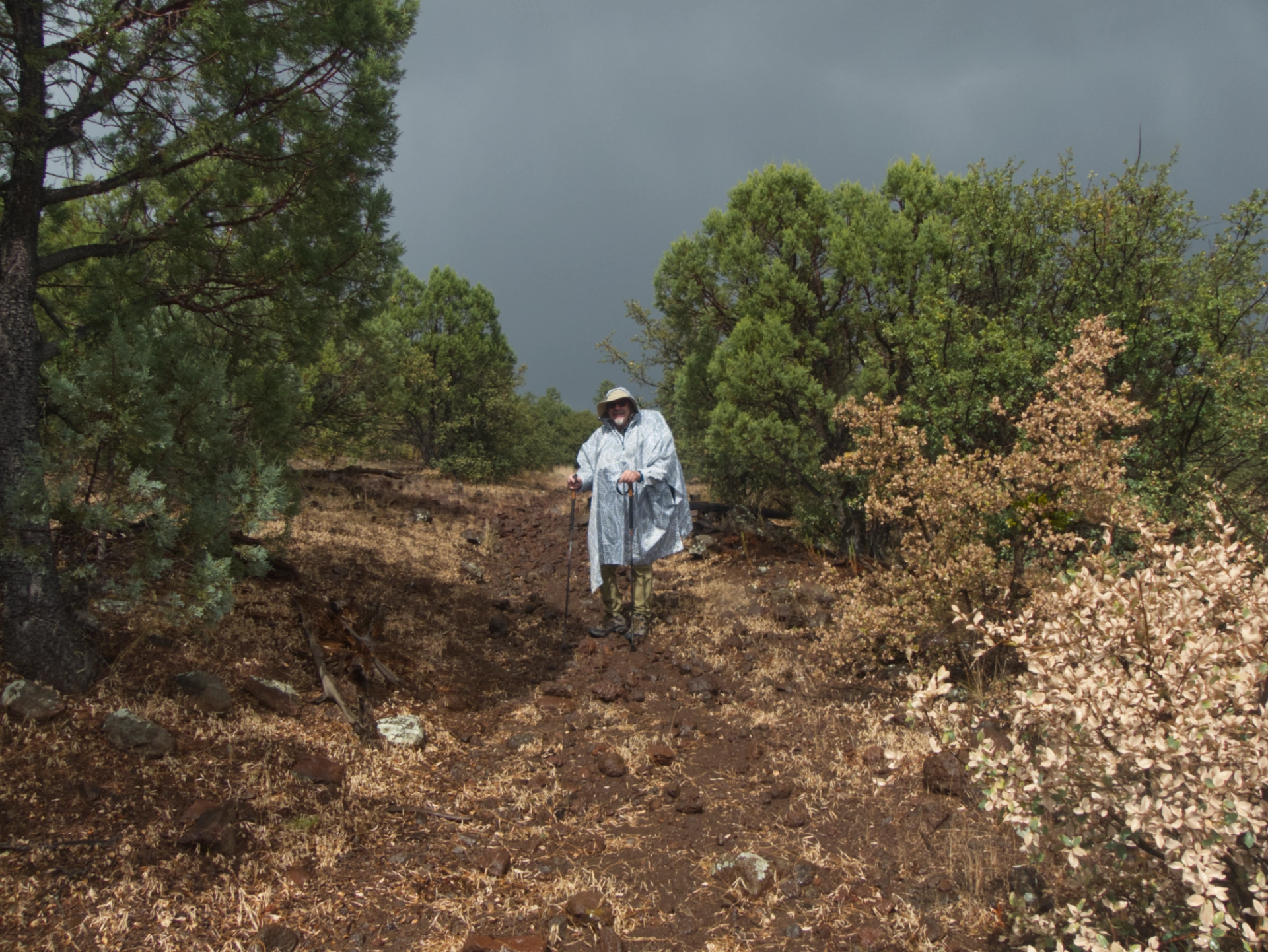 hiker in a rain poncho in mixed sun and clouds