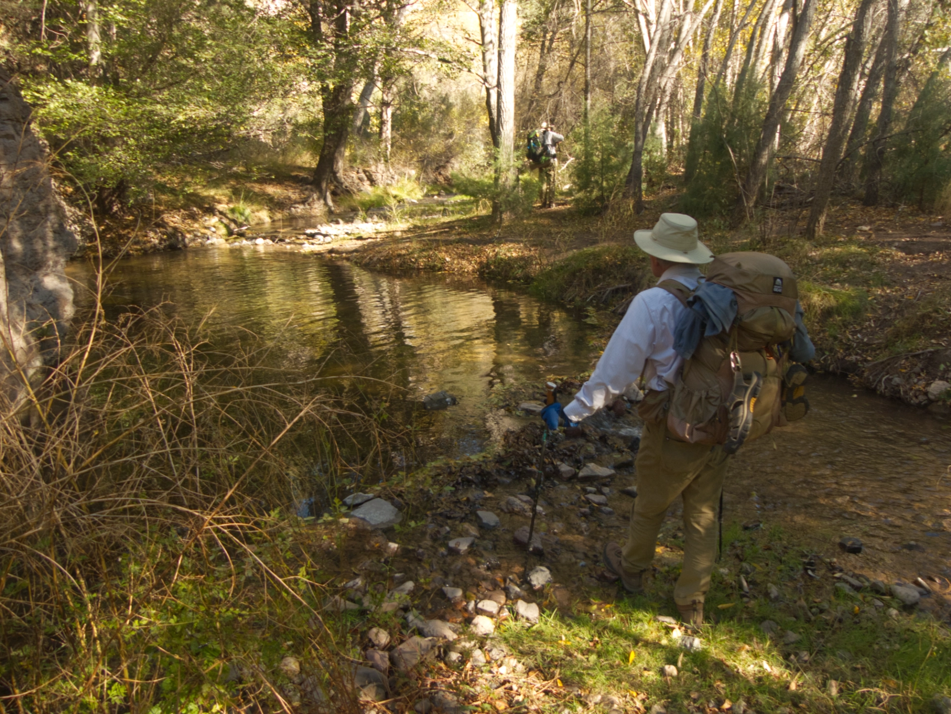 hikers crossing a creek in the shade