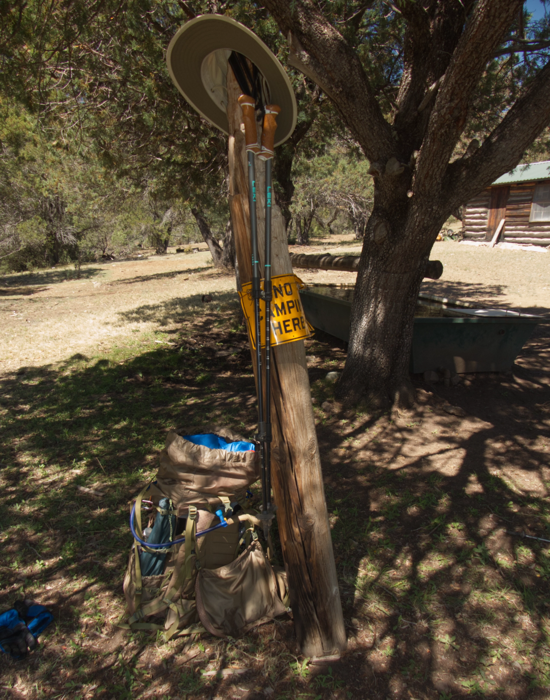 backpack, hat and poles leaning on no camping sign