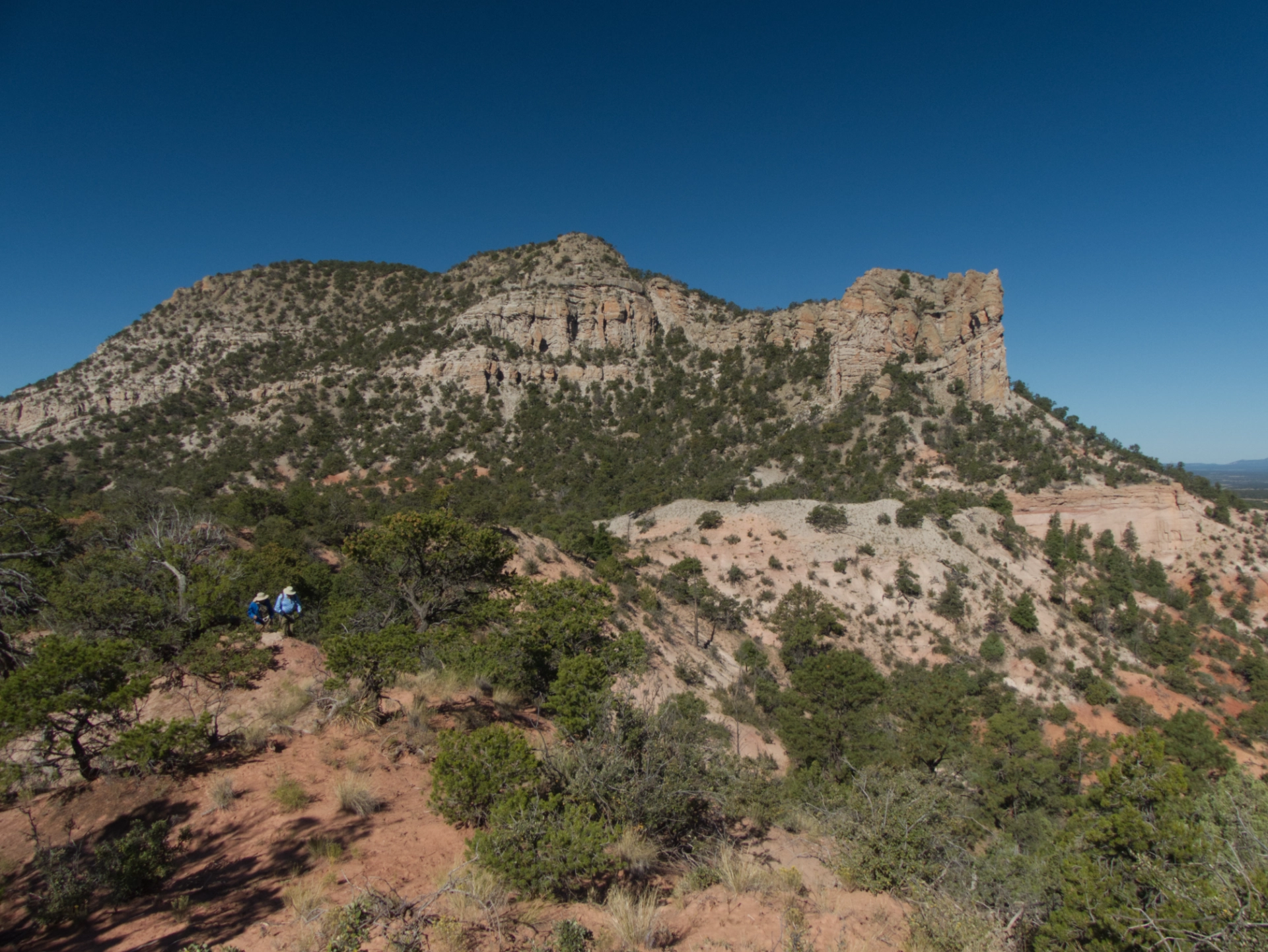 hikes scrambling along a sandy bridge between two peaks