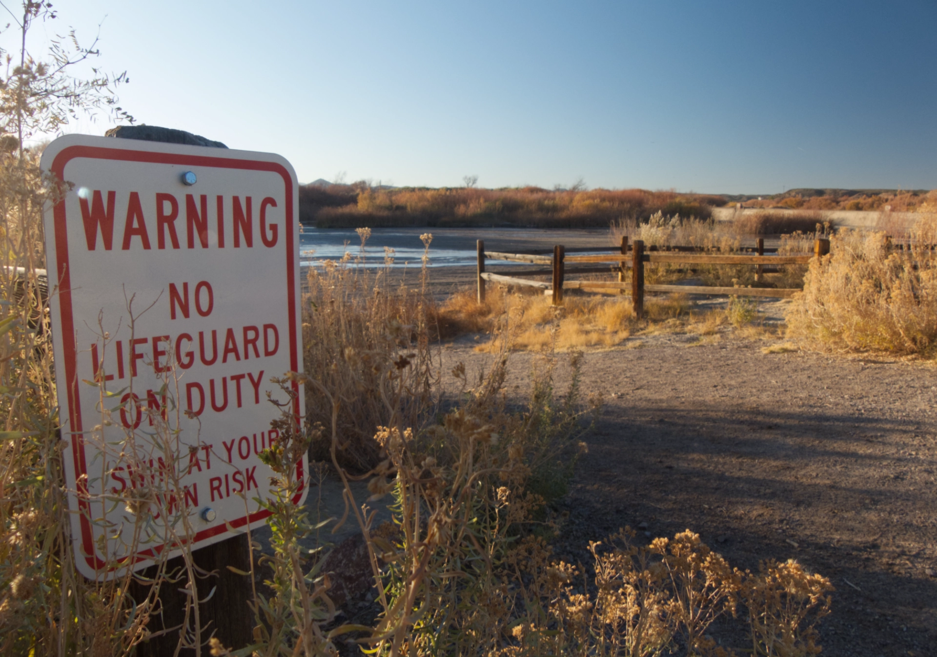 beach on a dry river with sign warning no lifeguard on duty