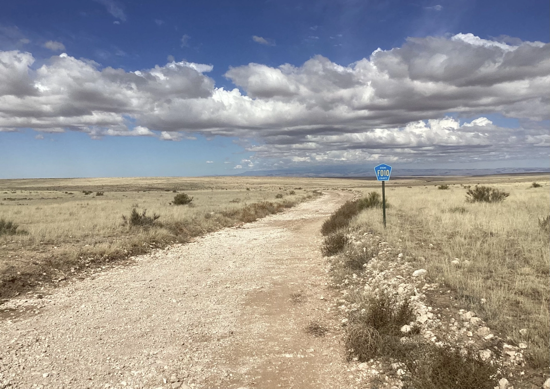rough gravel road across yellow grass prairie on Otera Mesa
