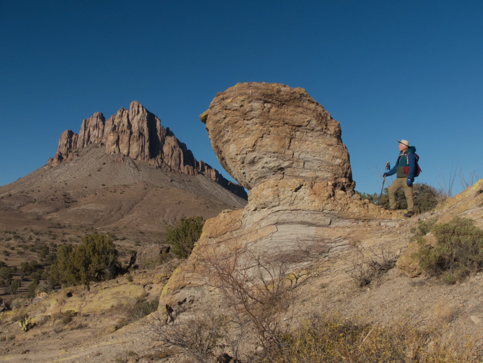 Dennis standing next to a rock hoodoo with Steeple Rock in the distance